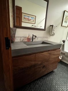 a bathroom sink sitting under a mirror next to a toilet paper dispenser