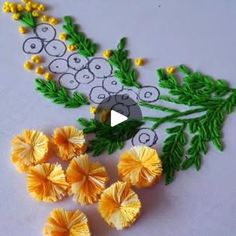 some yellow flowers and green leaves on a white table with an embroidered design in the middle