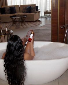 a woman sitting in a bathtub holding a bottle