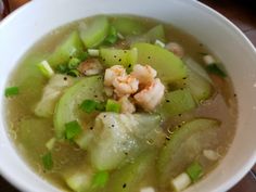 a white bowl filled with soup on top of a wooden table