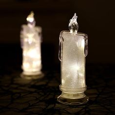 there are two glass bottles that have lights in them