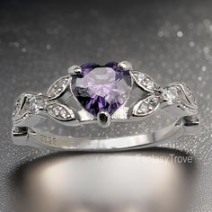 Brilliant sparkle with a lovely Violet Cubic Zirconia heart shaped stone, this White Gold promise ring has a core of solid 925 Sterling Silver, making it hypoallergenic and built to last!  The high-quality faceted heart stone is 6mm (0.8 carat) and has a Mohs hardness of 8-1/2.  Sprinkled generously with cubic zirconia rhinestones, this enchanting ring is accented by a nature-inspired tree branch and leaf design. It would make a great promise ring or engagement ring, as well as an excellent gift for Valentine's Day, Birthdays and other special occasions! Pictures were taken both indoor and outdoor to best represent color, but please keep in mind that your computer screen or handheld device may show a slightly different shade. Your treasure will be promptly shipped from the United States an Cubic Zirconia Heart Ring For Promise, Cubic Zirconia Heart Promise Ring, Silver Heart Crystal Promise Ring, Silver Cubic Zirconia Heart Cut Ring, Fine Jewelry Heart Shaped Cubic Zirconia Ring, Gemstone Heart Ring With Cubic Zirconia, Purple Heart Cut Amethyst Promise Ring, Heart-shaped Cubic Zirconia Promise Ring, Silver Heart-shaped Crystal Promise Ring