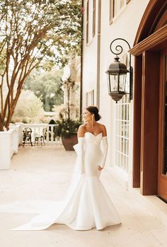 a woman in a white wedding dress is standing outside