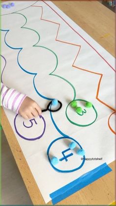 a young child is using scissors to cut out the letters on a large paper sheet