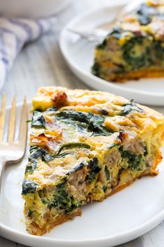 a slice of quiche with spinach and cheese on a white plate next to a fork