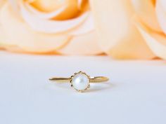 a close up of a ring on a table with flowers in the background and a rose behind it