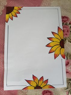 a paper with sunflowers painted on it sitting on a tablecloth covered surface