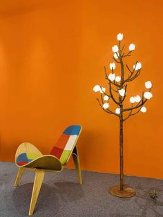 a chair and a tree with lights on it in front of an orange painted wall