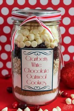 a jar filled with white chocolate covered cookies on top of a red and white polka dot table