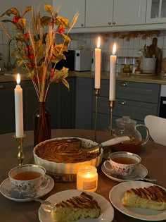 a table topped with plates and cups filled with food next to candles on top of a counter