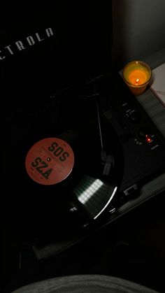 a record player sitting on top of a table next to a candle