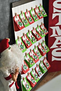 a santa clause figurine standing in front of a christmas calendar on a wall