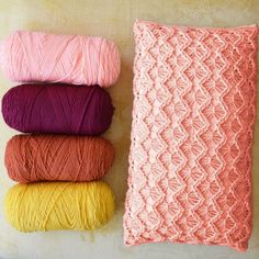 three skeins of yarn next to a crocheted blanket