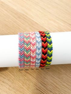 four different colored bracelets sitting on top of a white paper napkin next to a wooden table