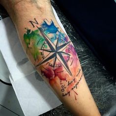 a man's arm with a watercolor compass tattoo on it and the words never give up