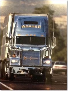 a blue semi truck driving down the road