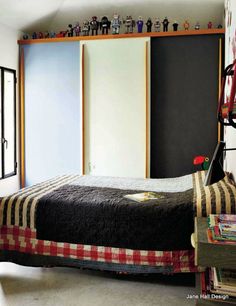 a bedroom with a bed, bookshelf and shelves on the wall above it