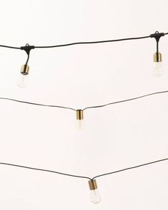 some lights are hanging on a wire against a white wall with no one in it