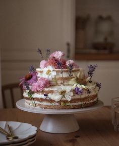 a cake sitting on top of a wooden table next to plates and utensils