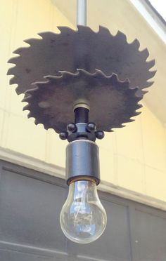 a light that is hanging from the side of a building with a large metal object attached to it