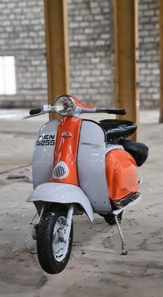 an orange and silver scooter parked in front of a brick building