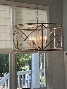 a chandelier hanging from the ceiling over a dining table in front of a window