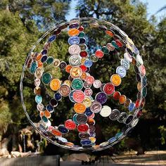 a circular sculpture made out of many different colored glass buttons in the shape of a peace sign