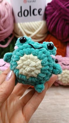 a hand holding a small crocheted frog