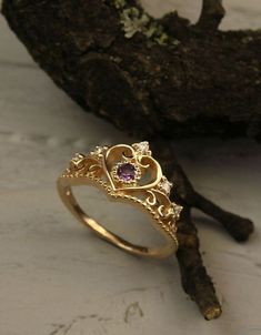 a gold ring with an amethorate stone in the center on top of a piece of driftwood