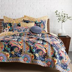 a bed covered in a blue and yellow comforter next to a white brick wall