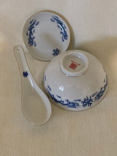 two blue and white dishes with spoons next to each other on a tablecloth