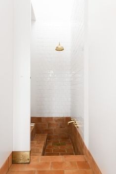 an empty bathroom with white walls and brown tile