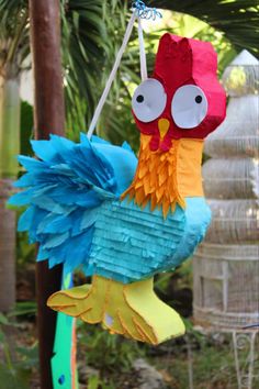 a colorful paper chicken hanging from a tree