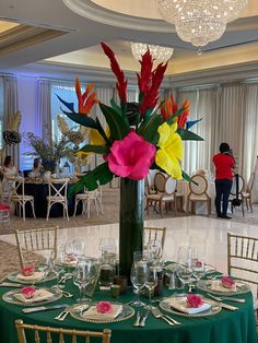 a vase filled with flowers sitting on top of a table covered in plates and glasses