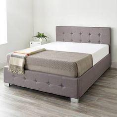 a bed that is in the middle of a room with wood floors and white walls