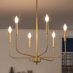 a chandelier with five lights hanging from it's center, in a living room