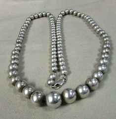 "Graduated sterling silver bead necklace. 25 1/4\" long. The center bead is 12 mm. The smallest beads in back are 6 mm. The beads are strung on chain and have a lobster claw clasp. There is some natural patina on the beads so the look is softer, not too bright and shiny. Good condition. This is a classic timeless look. Good condition. BDS-2" Elegant Hand-strung Sterling Silver Necklaces, Sterling Silver Single Strand Beaded Necklace, Silver Beaded Necklace With Oval Beads, Silver Jewelry With Single Strand Oval Beads, Sterling Silver Necklaces With Hand-strung Round Beads, Classic Round Beaded Necklace With Sterling Silver Clasp, Sterling Silver Single Strand Beaded Necklaces, Silver Round Beaded Necklaces Hand-strung, Sterling Silver Round Beaded Single Strand Necklace