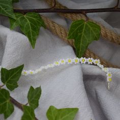 white flowers and green leaves are tied to a piece of rope on the table cloth