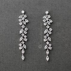 two pairs of diamond earrings on a gray surface