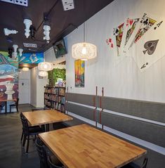 a restaurant with tables and chairs in front of a wall covered with cards on it