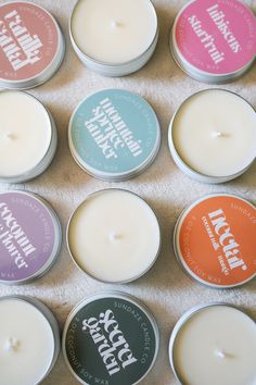 six different types of candles sitting next to each other on a white cloth covered table