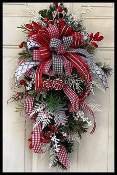 a red and white christmas wreath hanging on a door