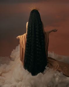 a woman with long black hair sitting on top of clouds