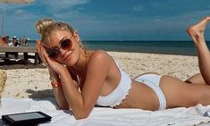 a woman laying on top of a beach next to an umbrella