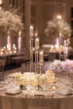 the centerpieces in this wedding reception are tall, slender candles and white flowers