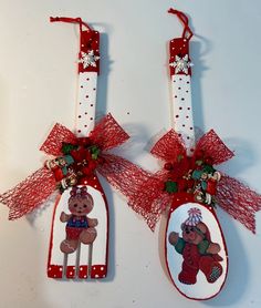 two red and white christmas spoons decorated with teddy bears on them, hanging from strings