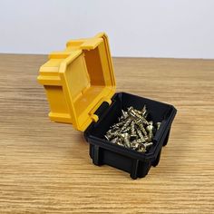 a yellow and black container filled with lots of screws on top of a wooden table