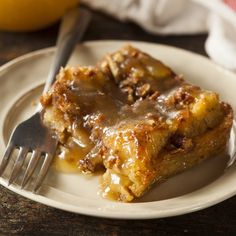 a white plate topped with two pieces of cake covered in caramel sauce next to a fork