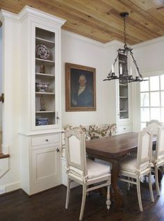 the dining room table is surrounded by white chairs and cupboards, along with an old - fashioned china cabinet