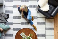 a woman is sitting on the floor in her living room looking down at some flowers